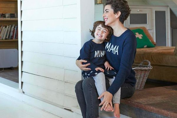 一位法国父母与谁穿着坐在她的腿上同样的衬衫孩子。