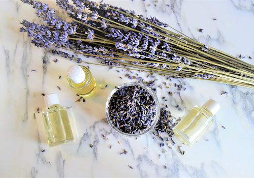 Fresh lavender on a table surrounded by bottles of essential oils.