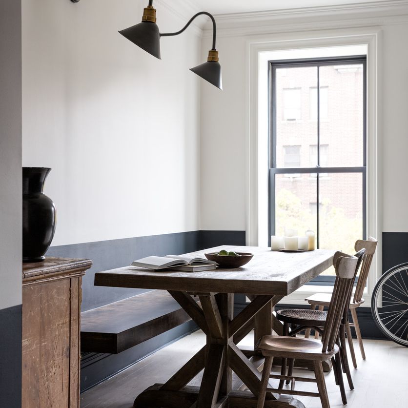 餐厅的一端是一碗水果和一本书，另一端是顶部有蜡烛柱的托盘