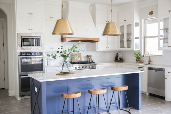 白色厨房，蓝色岛和金色吊灯。