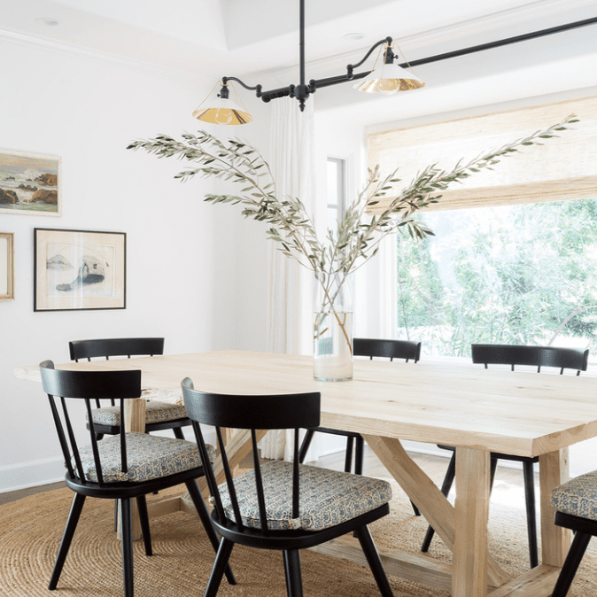 一张木制餐桌，上面有一个装满大树枝的玻璃花瓶