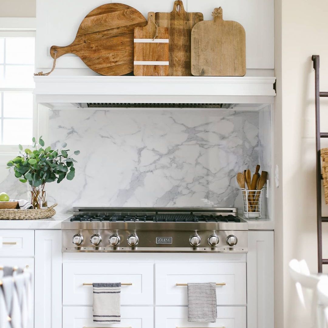 有大理石backsplash和葡萄酒切板显示的白色厨房