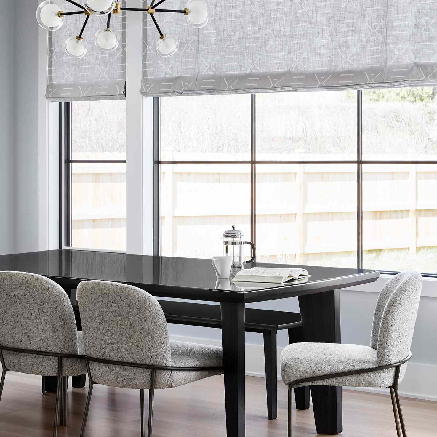 一张黑色的餐桌，上面放着一本书，一个法式压滤机和一个咖啡杯