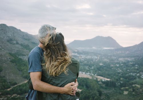 一对俯瞰大山的夫妇拥抱在一起