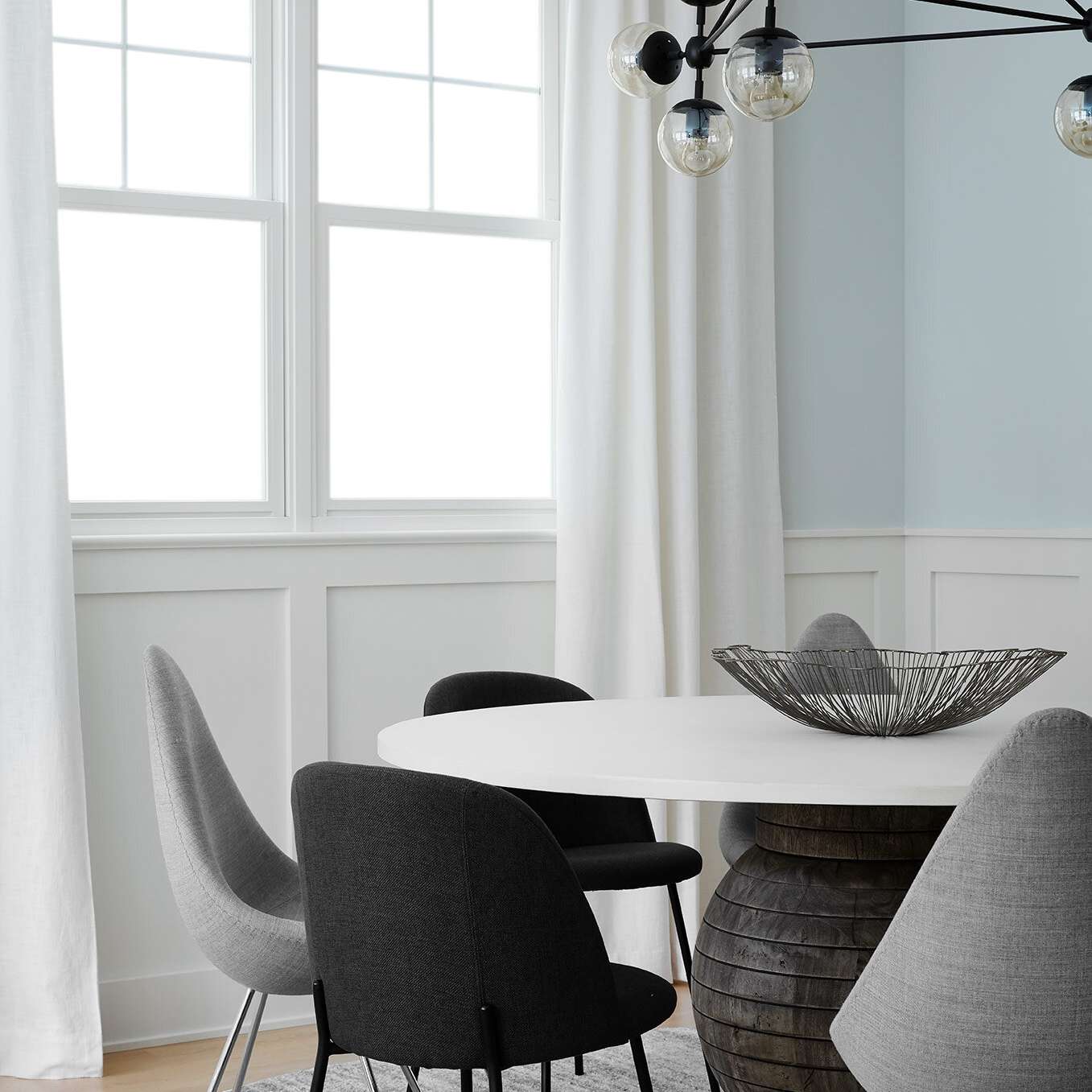 黑色、白色和灰色的餐厅，黑色窗帘杆上挂着白色窗帘