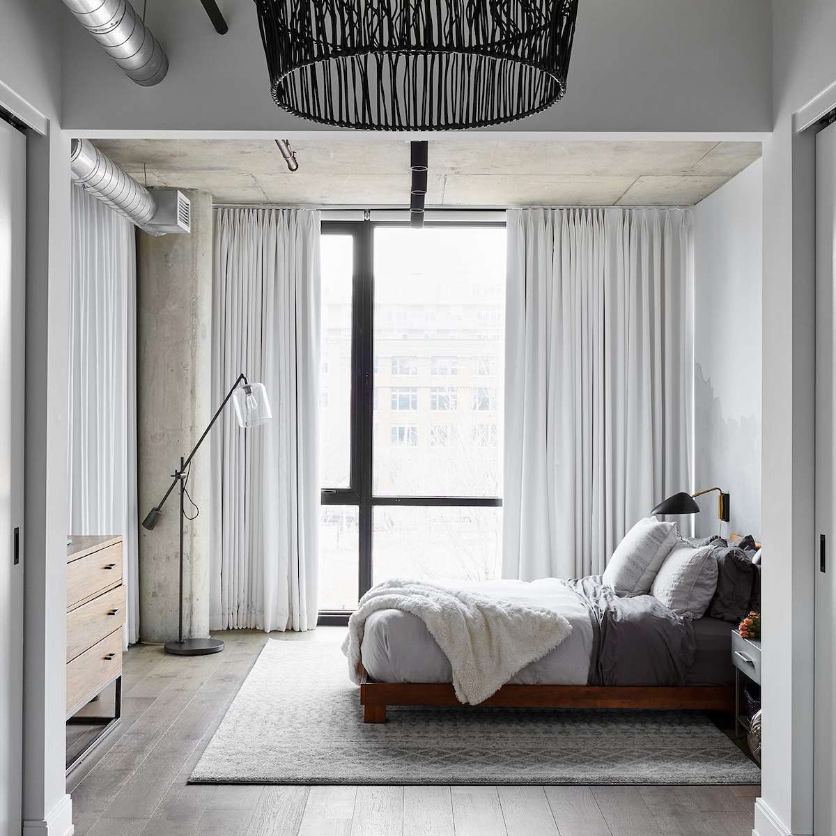 一间带有编织吊灯、现代壁灯和工业落地灯的工业卧室