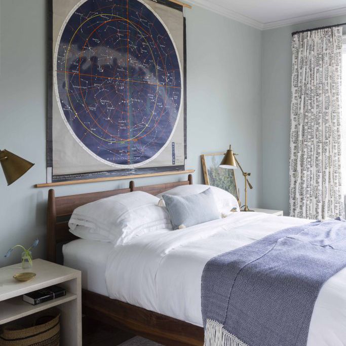 一间带蓝色毯子，墙壁和艺术的卧室