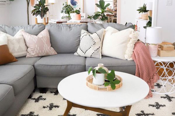Living room with gray couch and lots of plants.