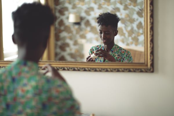 一个女人在寻找一个面霜反映在镜子。