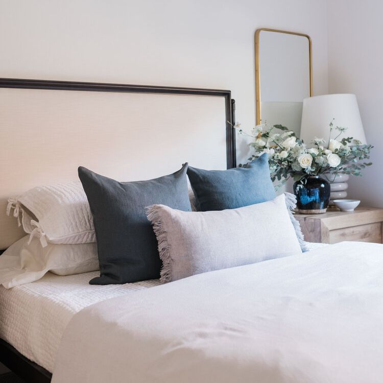 中性床，亚麻枕头和木制床头柜。