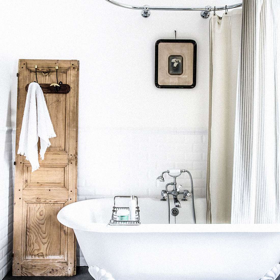 有clawfoot的浴缸，一个老式的照片，并拿一块毛巾浴室架从古董门口走去