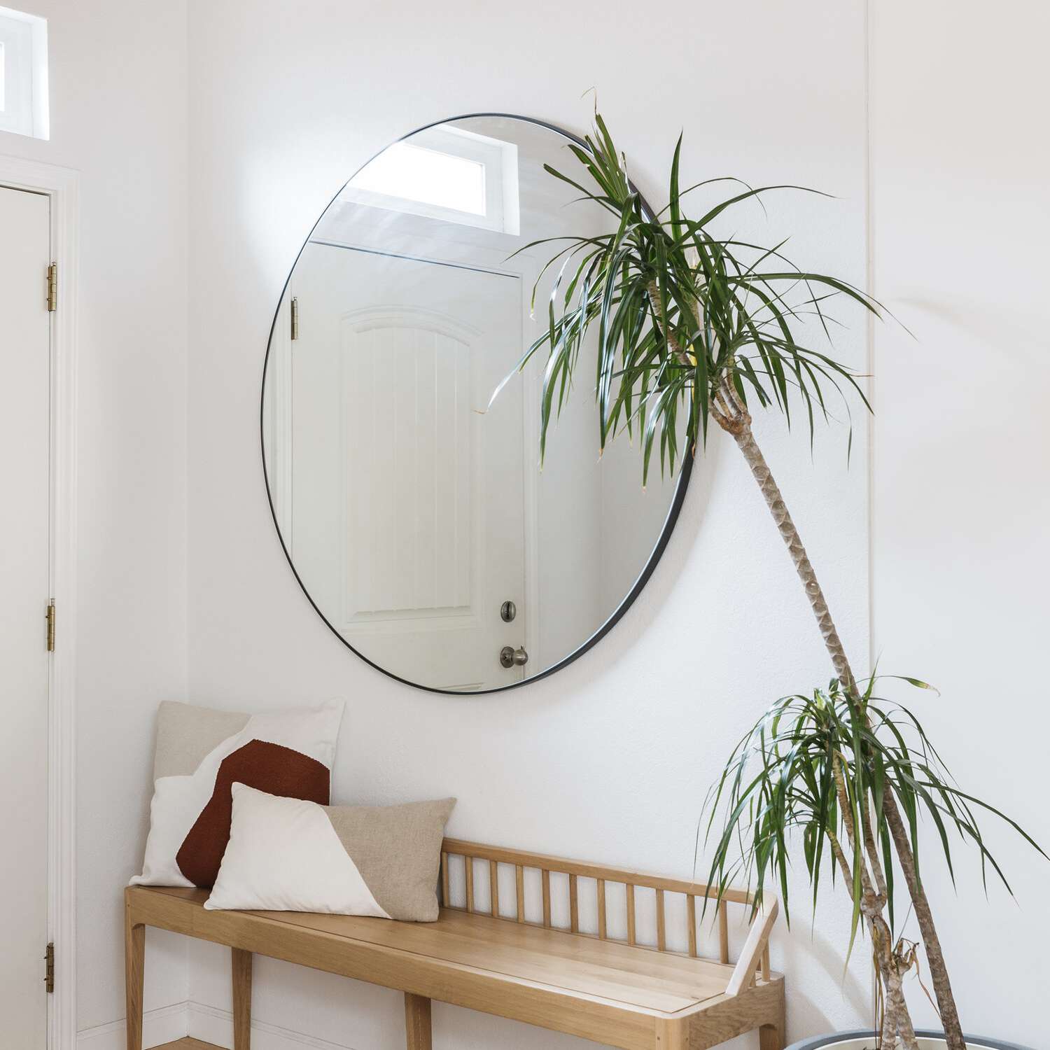 入口处装饰着一张长凳，上面放着米色和紫红色的印花枕头