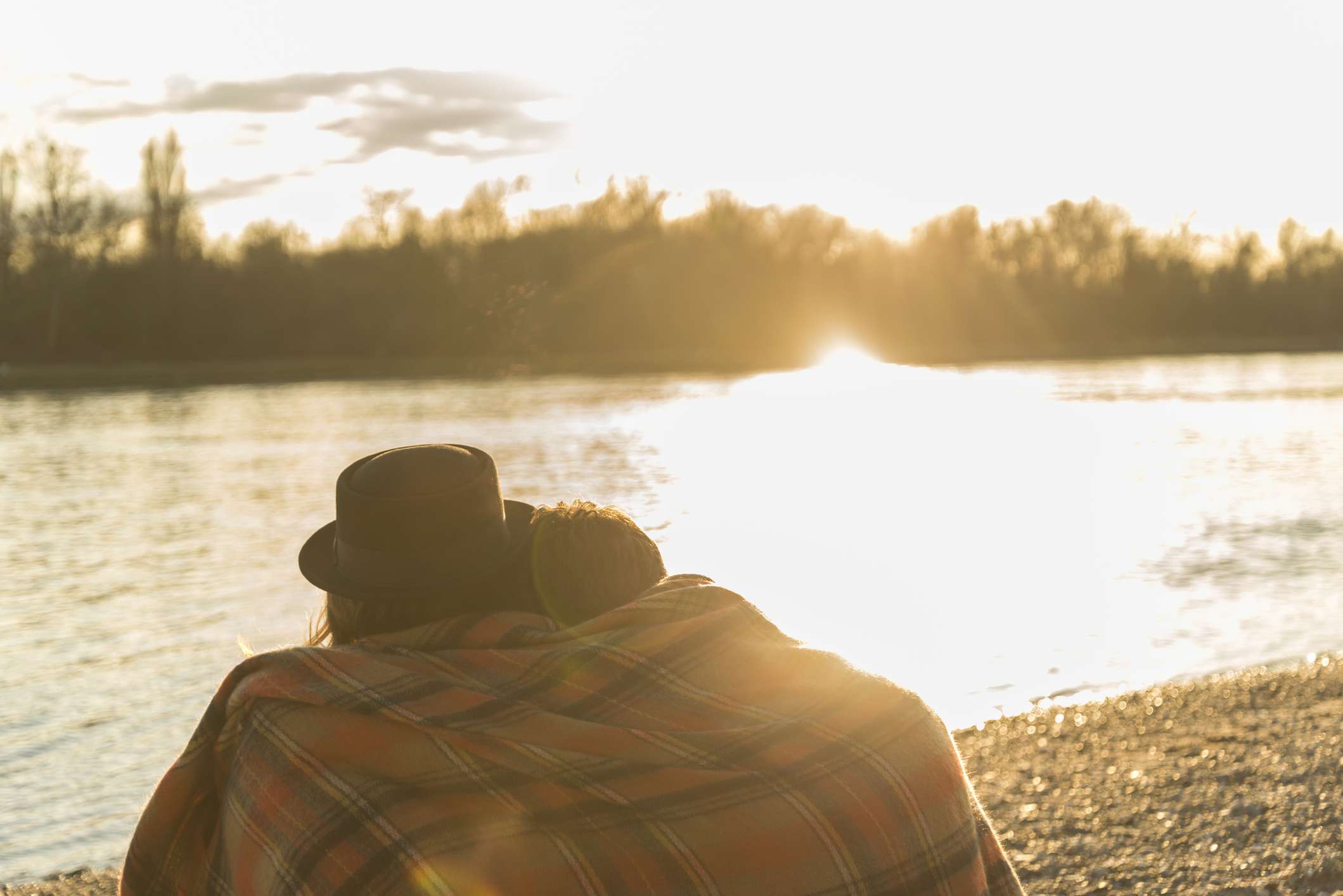 夫妇裹在毯子看日落附近的水体