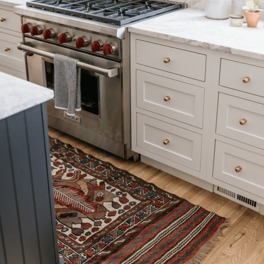 一个白色的厨房，有深红色印刷地毯