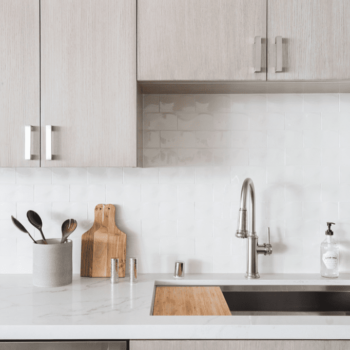 灰灰色木橱柜的厨房和用闪亮的白色瓷砖排列