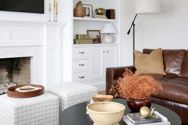 客厅有黑色桌子，两个ottomans和棕色皮革沙发。