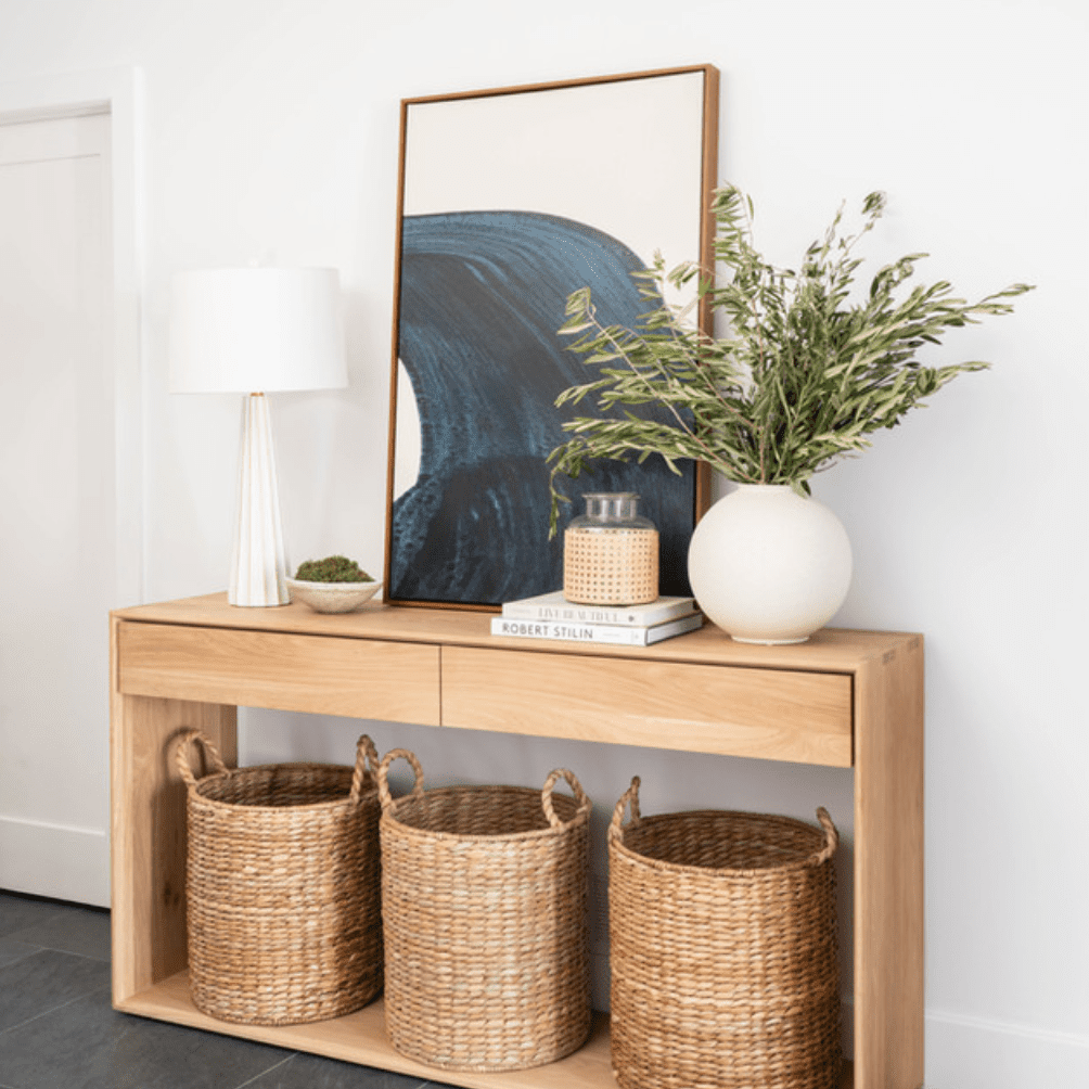 一个木制控制台桌，装饰着抽象艺术和几个编织的篮子