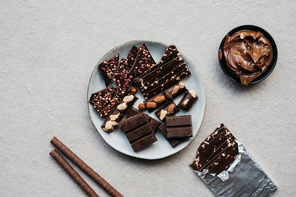 Top view of different kind of chocolates bars pieces and chocolate cream over cement background