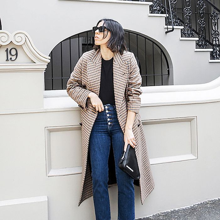 在牛仔裤的一个女人和一个格子风衣