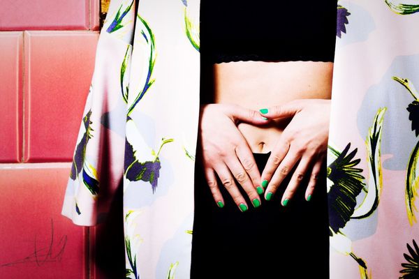 一个穿着长袍，双手捂着肿胀的肚子的女人。