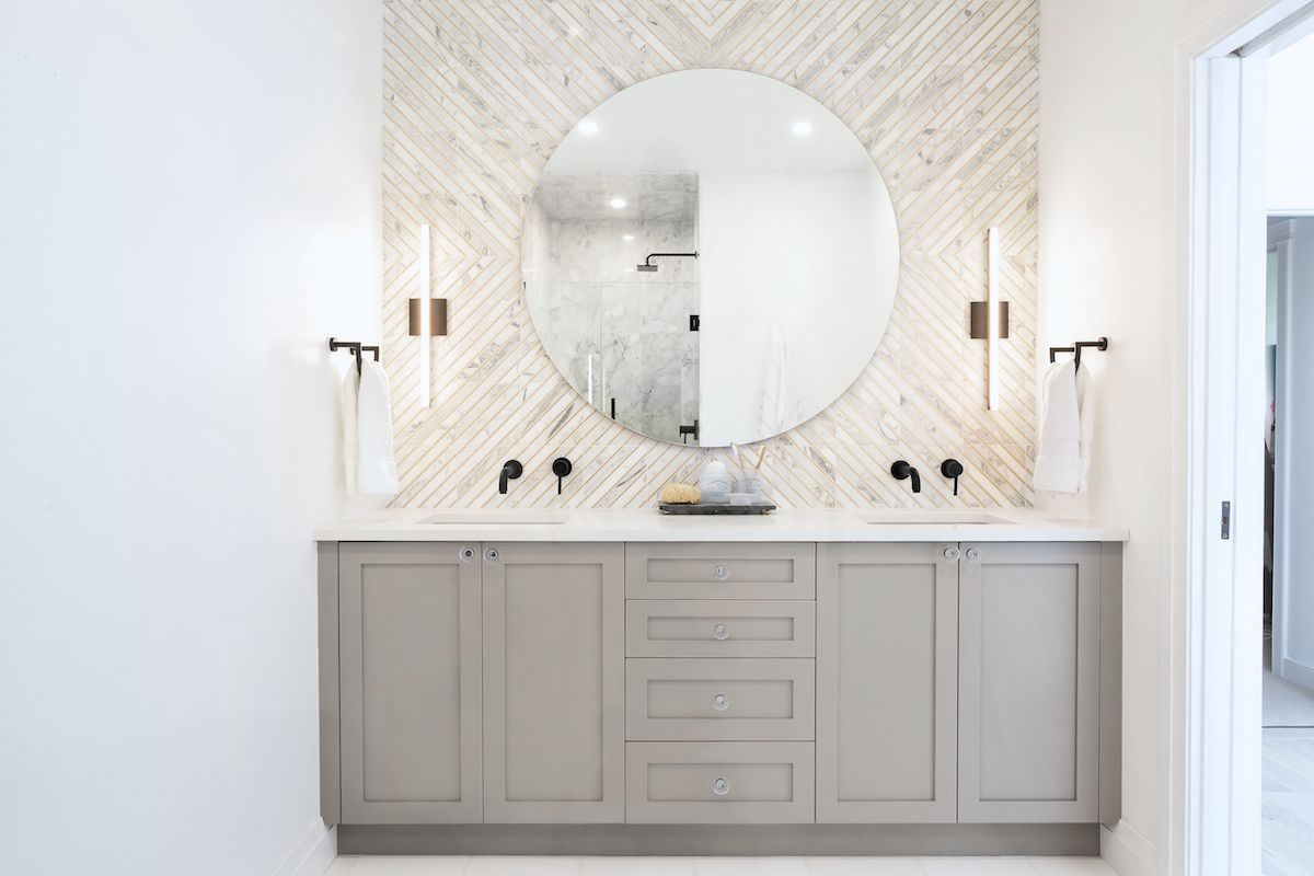 A bathroom with gray cabinets and a white tile-lined wall