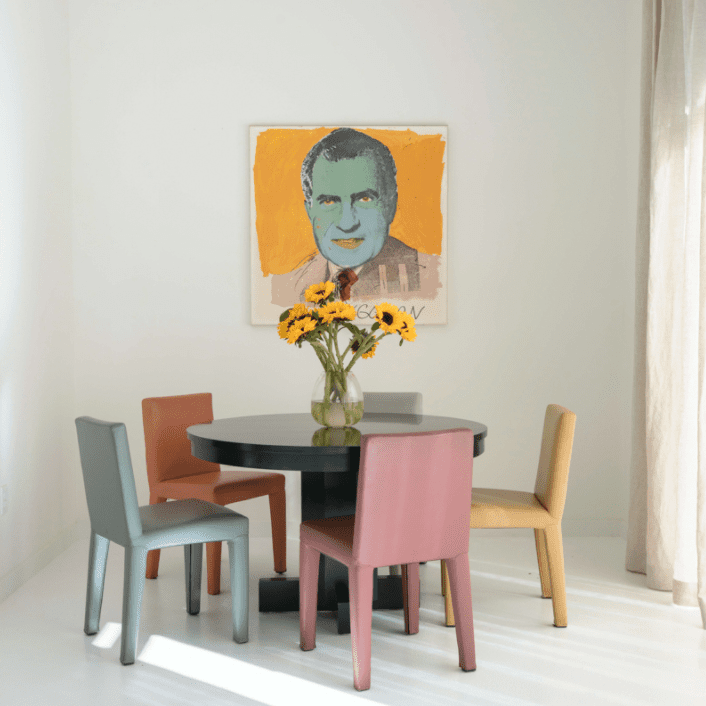 一张桌子，周围是五颜六色的椅子，旁边是一件现代艺术品