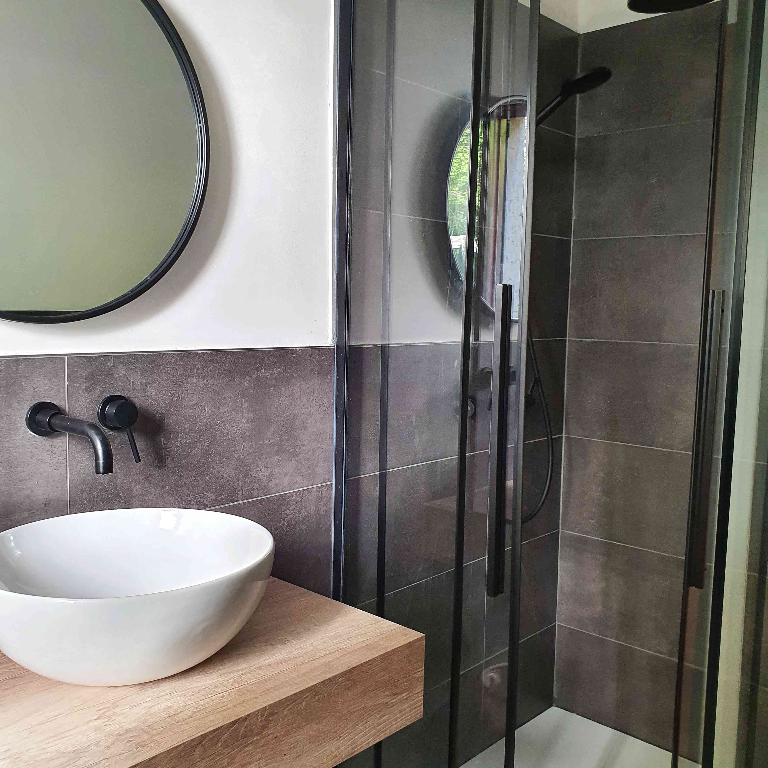 Susanne Pumpluen永远不会忘记的一个房间——黑色瓷砖淋浴，圆形镜子和白色水槽