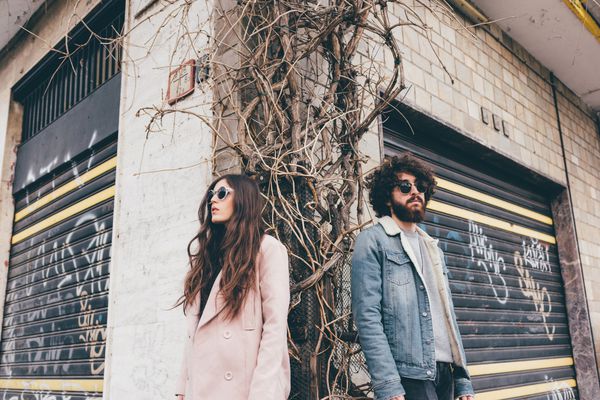 Portrait of young man and woman, standing on street corner, low angle view