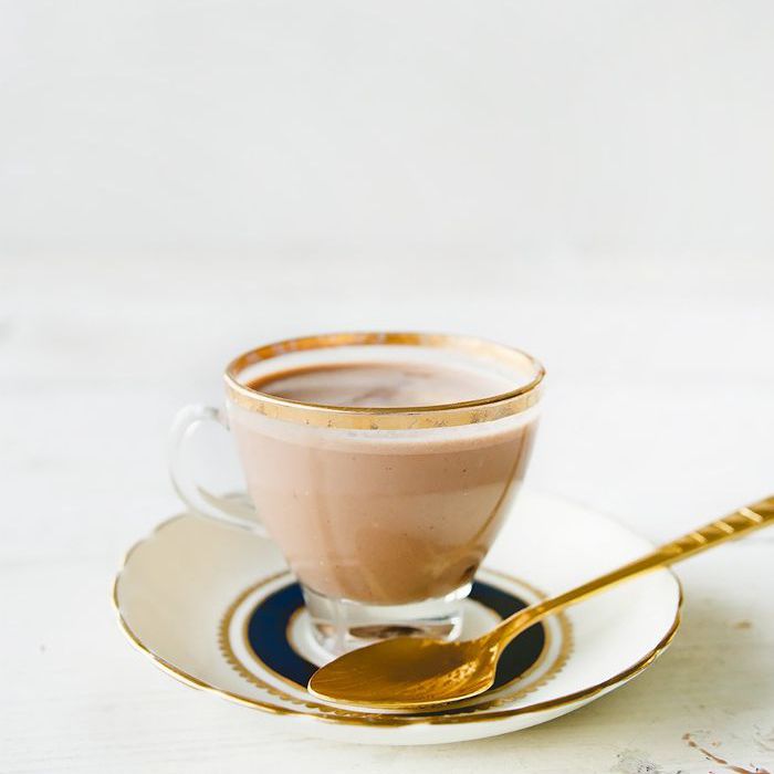 小咖啡玻璃全部的热巧克力，坐在一个扇形的瓷茶碟上有一个金汤匙休息。