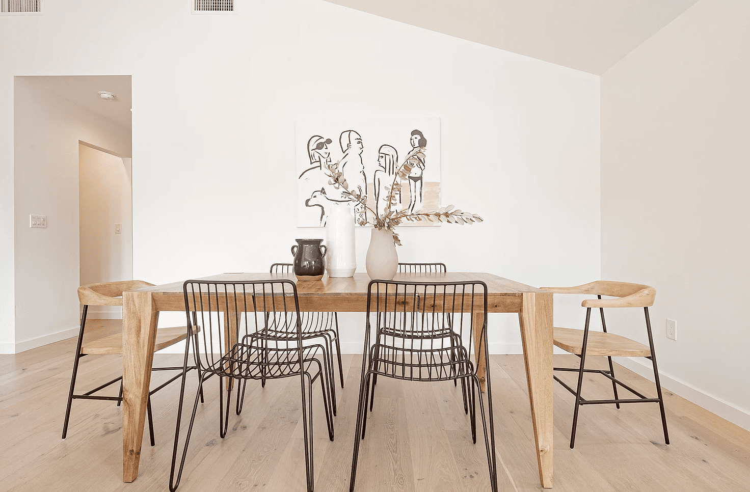 餐桌上有三个中性花瓶的木制餐桌