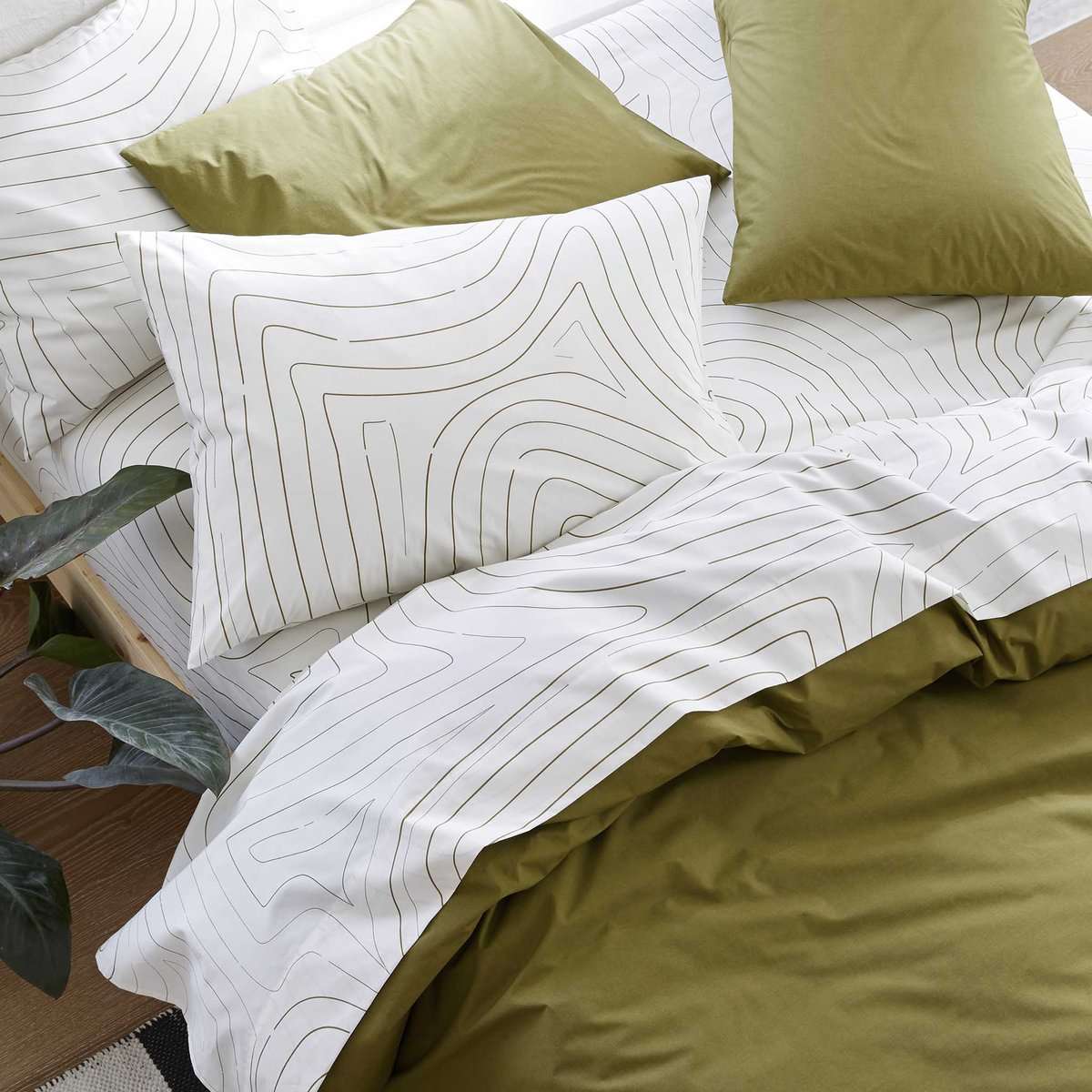 床上铺着白色床单，上面有波浪图案和绿色羽绒被
