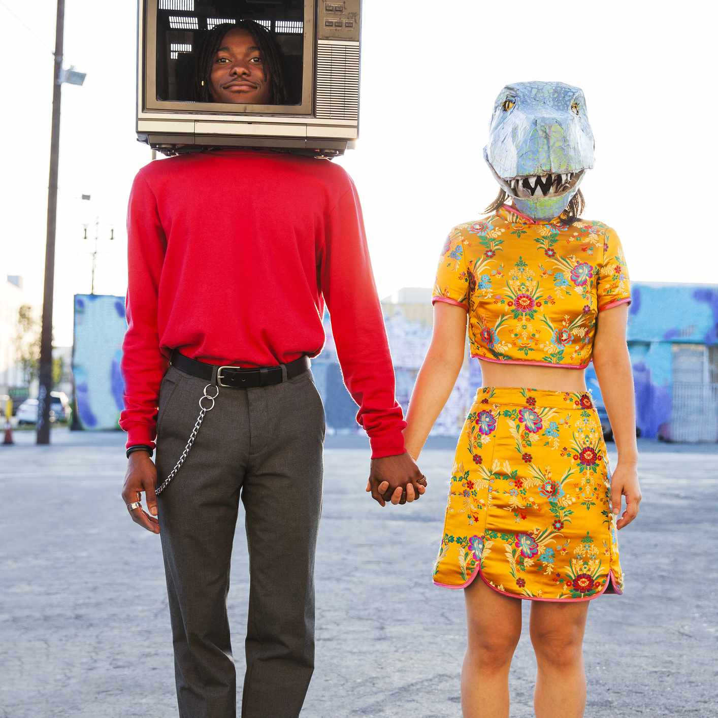 一个头戴电视的年轻人和一个戴着恐龙面具的女人。