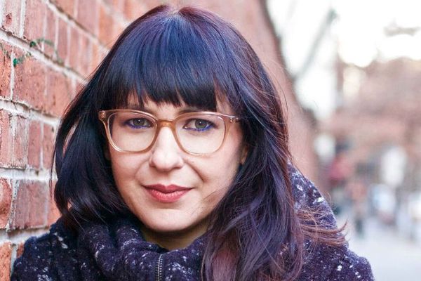 有黑发和玻璃的妇女在砖墙旁边