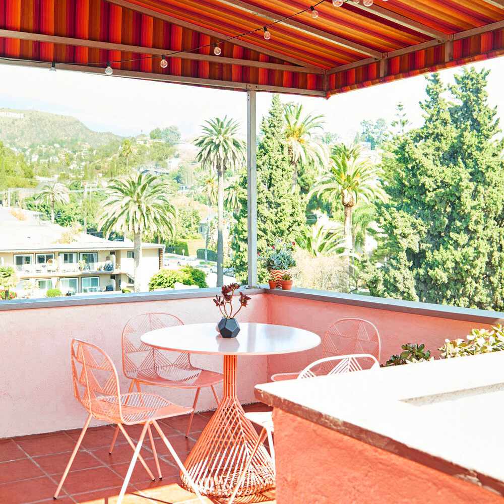 粉红色的阳台上装饰着粉红色的桌子和配套的椅子