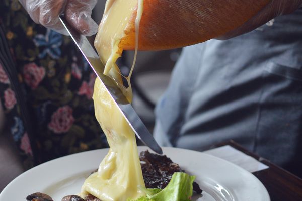 将融化的奶酪刮在土豆和蘑菇上的raclette奶酪轮