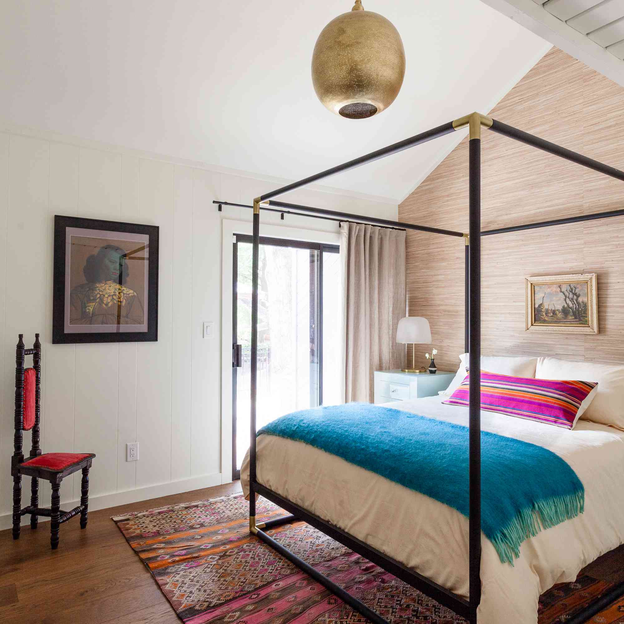 卧室配有树木床，金吊坠灯和洋红色扔枕头。