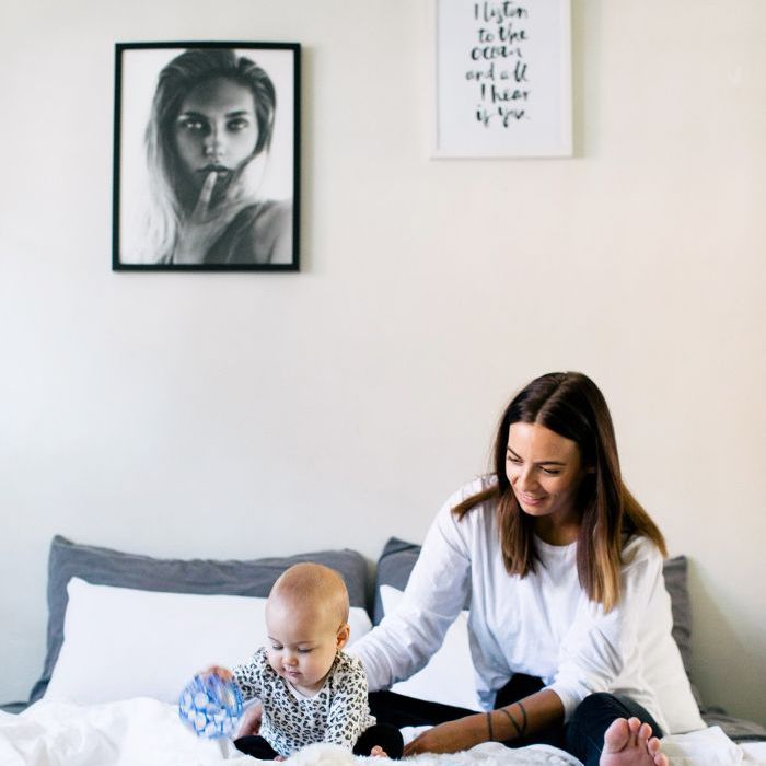 一个女人和婴儿在一张舒适的白色床上玩耍