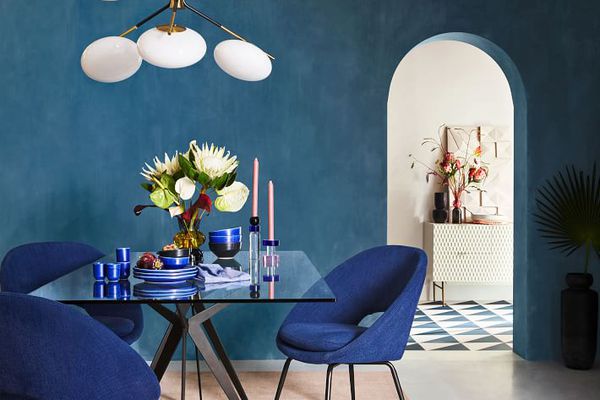 一间有蓝色墙壁的房间，里面有蓝色的椅子和两束人造花。