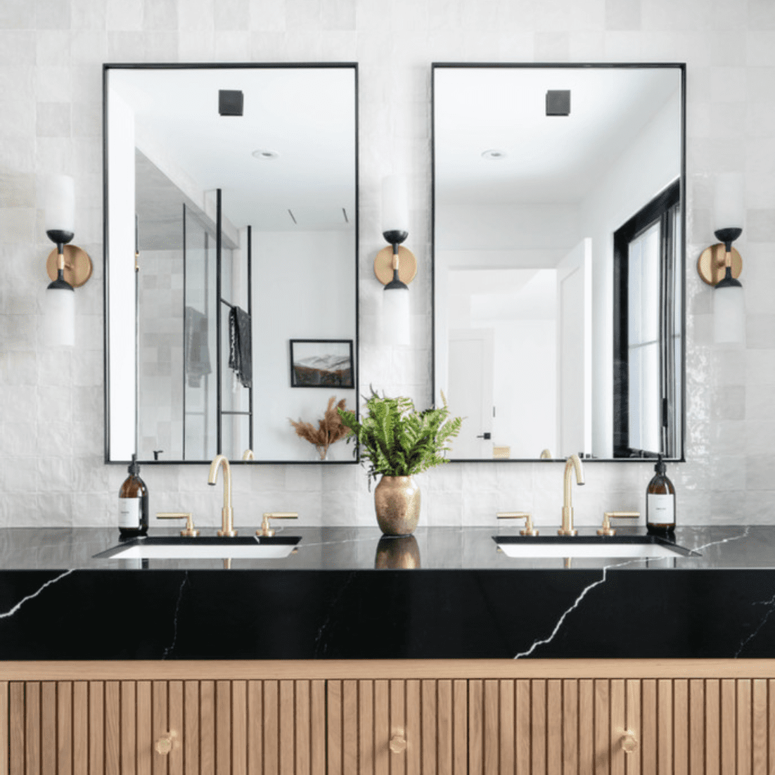 一间装饰艺术风格的浴室，带有浅浮雕木橱柜、黑色大理石台面和瓷砖内衬的后挡板