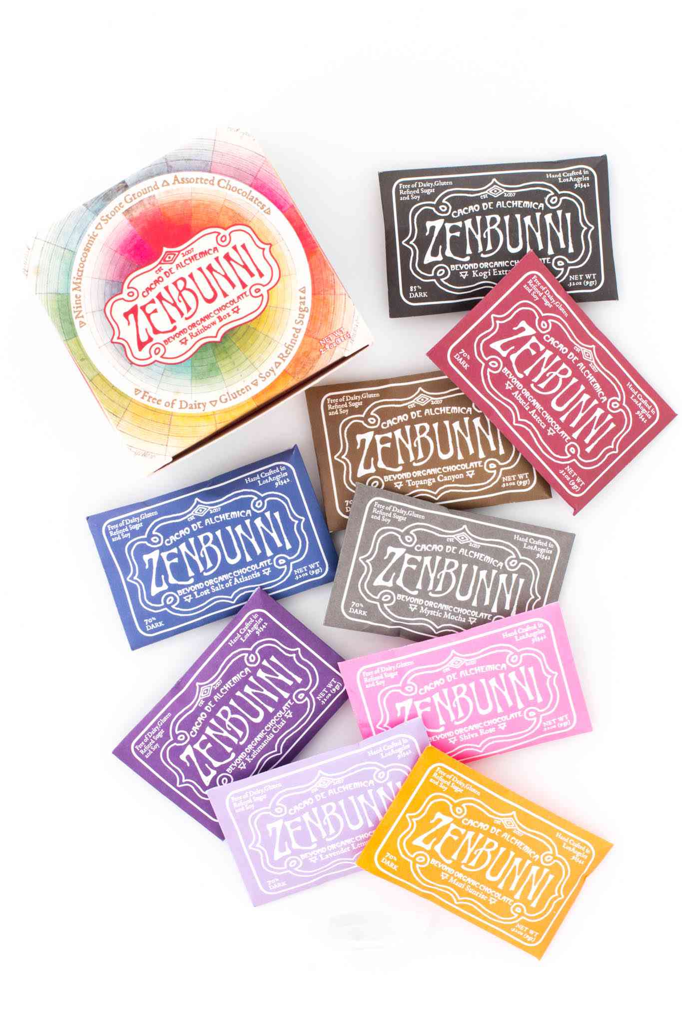 九块彩虹色纯素食巧克力，旁边有一个盒子。