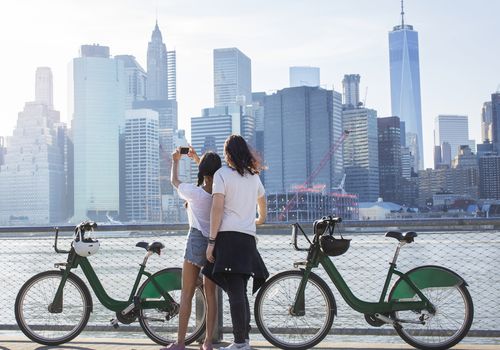 一对情侣在租来的自行车旁自拍，背景是地平线