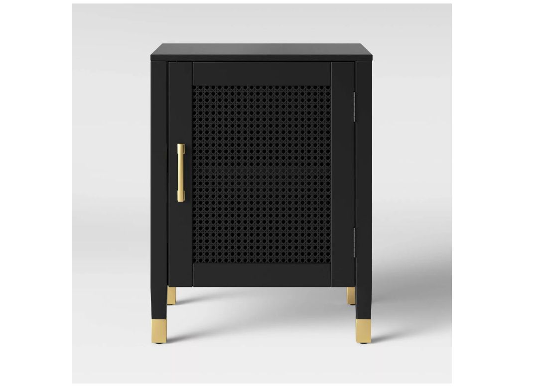 黑色的床头柜上有藤门，铜拉手，铜脚。