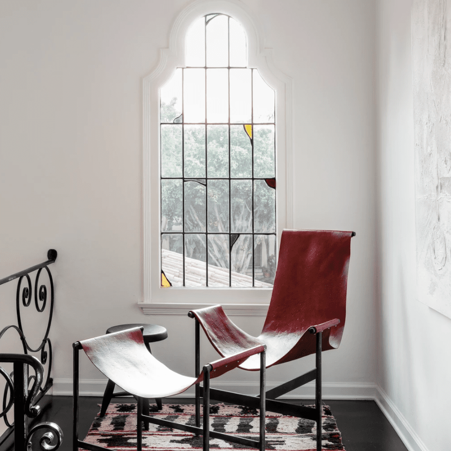 一面有彩色玻璃窗的墙，后面是一把红色的椅子