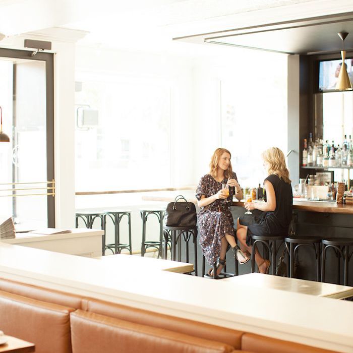 两个女人坐在酒吧彼此相对的，喝在手