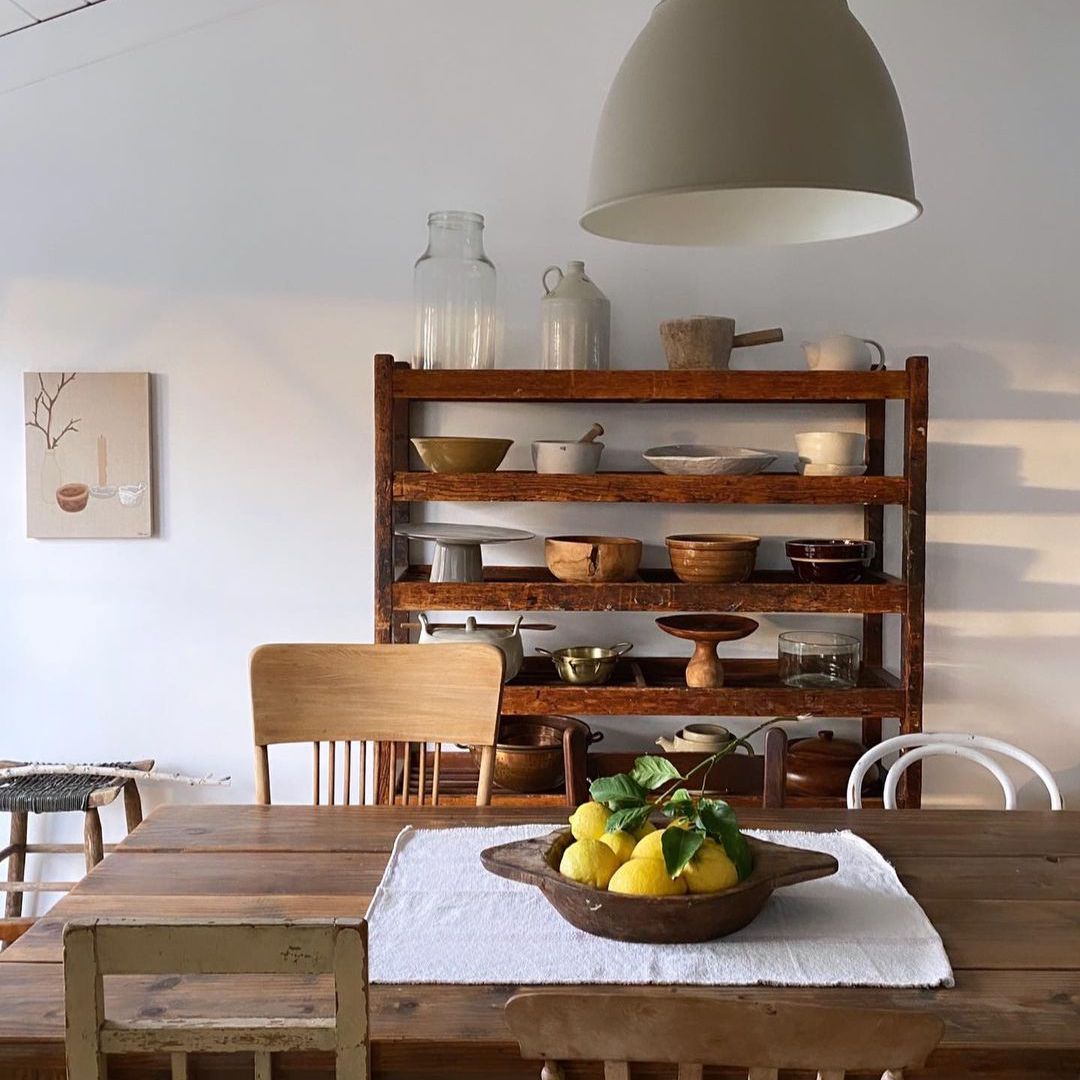 乡村厨房配有不相配的古董椅子和陈列古董盘子的架子