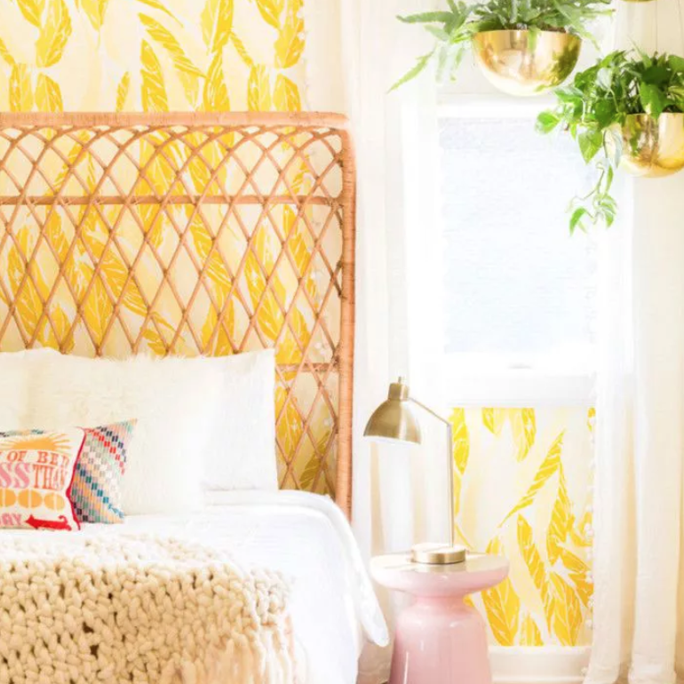 古怪的卧室，藤条床头板和黄色羽毛图案的墙纸。