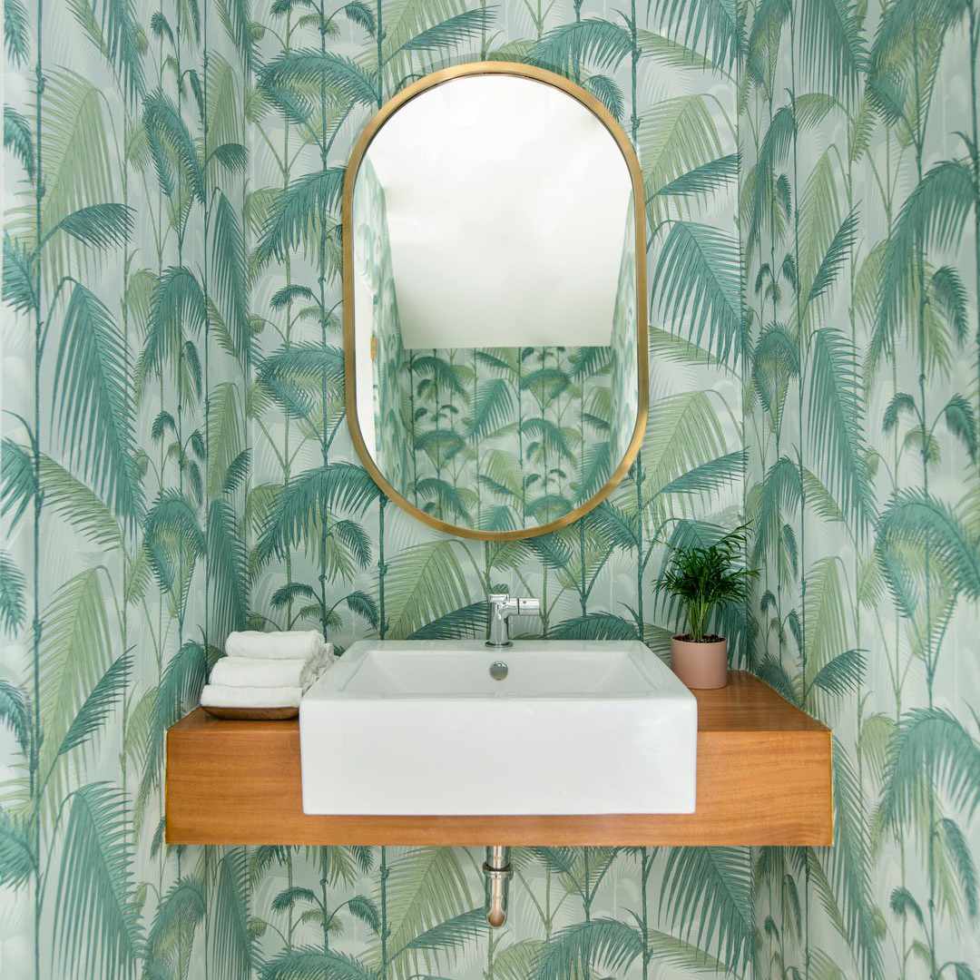 A powder room lined with vibrant tropical print wallpaper