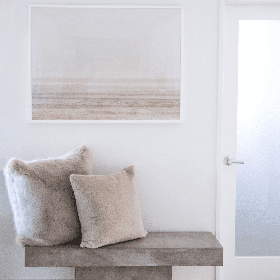 墙上装饰着小型水泥长凳和两个米色扔枕头