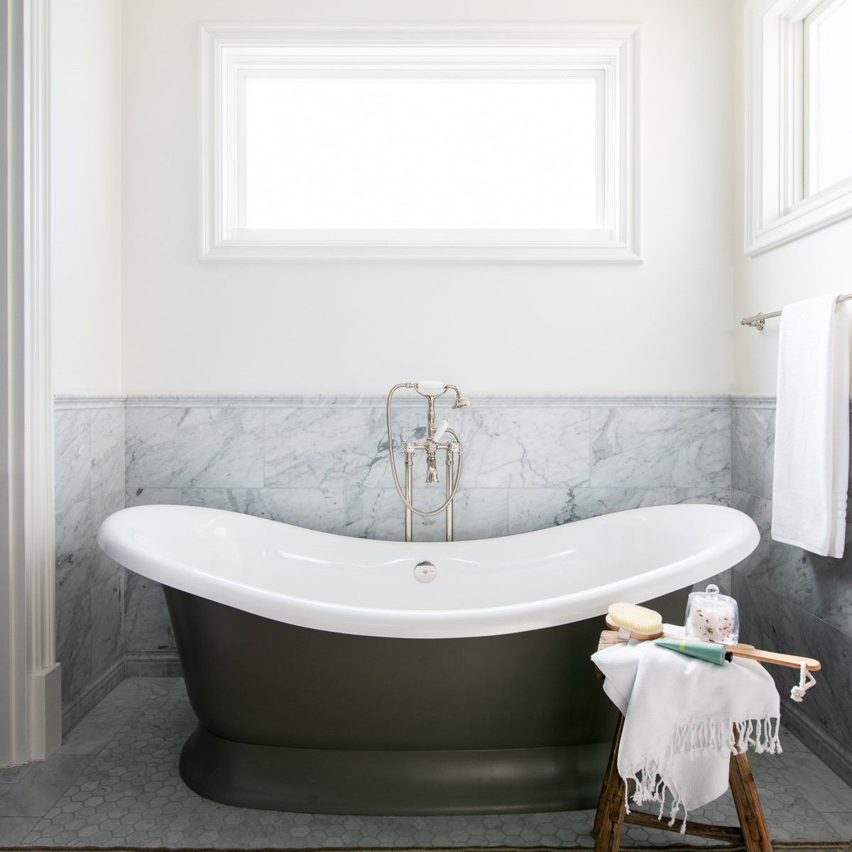 A bathroom lined with gray marble and a light brown printed rug