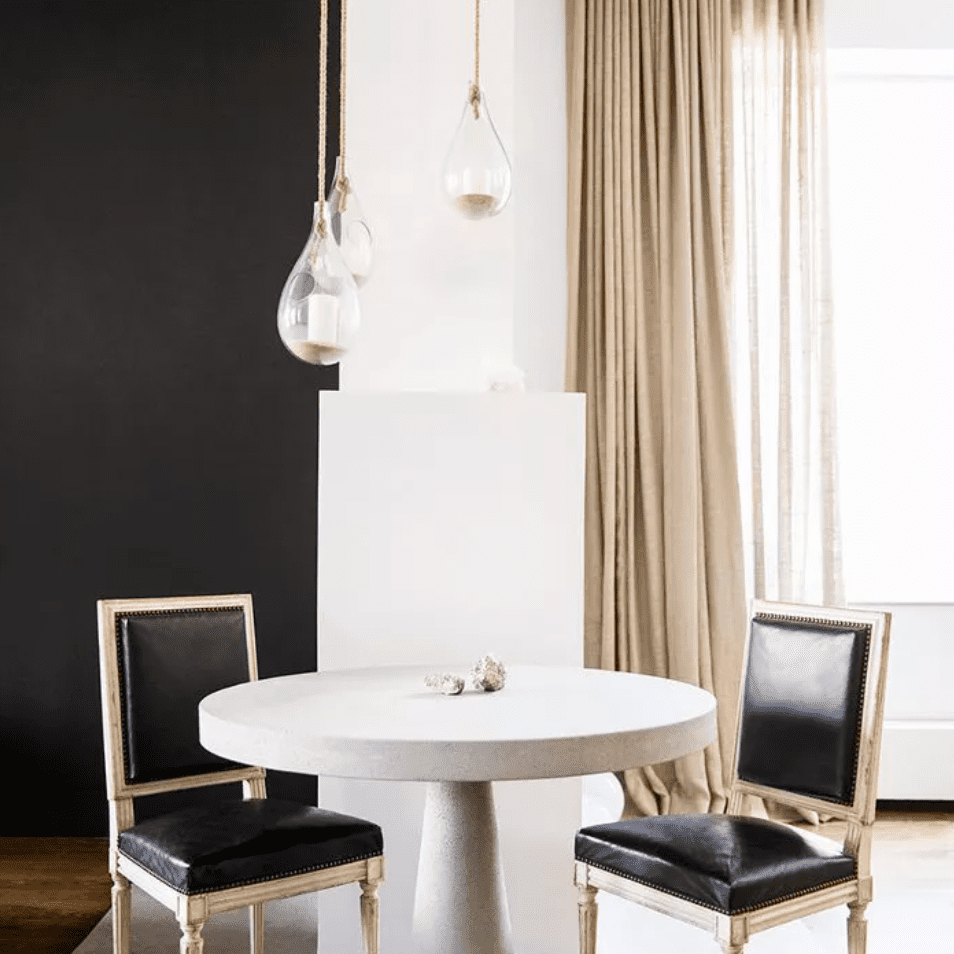 从地板到天花板的薄纱窗帘架着一张双座餐桌